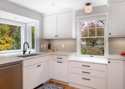 Modern kitchen with white cabinetry, stainless steel appliances, and a window overlooking a landscaped garden, highlighting the potential for renovations by Harding Builders.