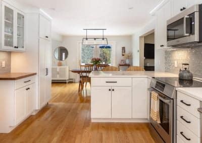 Modern kitchen interior with white cabinetry, stainless steel appliances, and wooden flooring, showcasing a functional layout ideal for home renovations and remodeling projects.